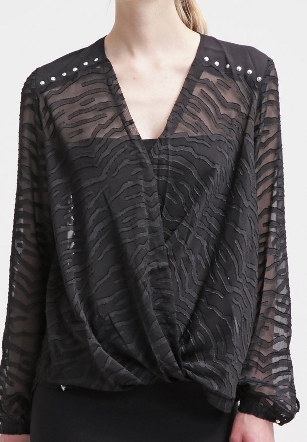 Blouse noire transparente à manches longues avec rayures zébrées texturées, col en V, détails cloutés aux épaules, et nœud froncé au niveau de la taille.
