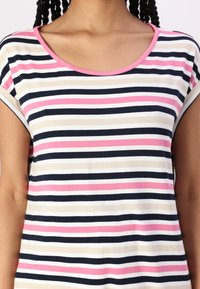 Stripet topp med rund hals. Har vekslinger mellom marineblå, kremfarget, lys rosa og mørk rosa striper. Mykt stoff og korte ermer.