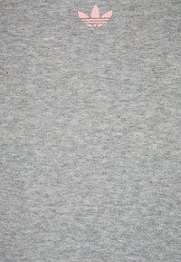 Grå sweatshirts i mjukt tyg, med ett subtilt fläckigt mönster av blå och rosa prickar samt en liten rosa logotyp i övre mitten.