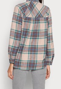 Camicia a quadri con una miscela di tonalità beige, blu e verde, con polsini abbottonati e dettagli sulla spalla sul retro. Realizzata in tessuto morbido e testurizzato.