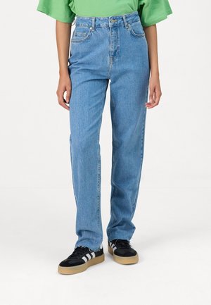 Hoge taille, lichtblauwe denim spijkerbroek met een rechte pasvorm en minimale slijtage, gecombineerd met zwarte sneakers met witte strepen.