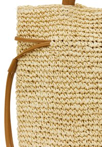Geweven stro totebag in natuurlijk beige met bruine leren accenten en een gestructureerd oppervlak. Beschikt over een duurzame, versterkte handgreep voor gemakkelijk dragen.