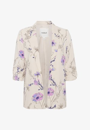 Blazer beige avec imprimé floral en violet et bleu, présentant des manches retroussées et un design à ouverture frontale. Étiquette visible à l'intérieur.