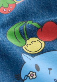 Denimová tkanina s barevnými ilustracemi usměvavé žluté tváře, červených třešní a modré kočky s květinou na modrém pozadí.