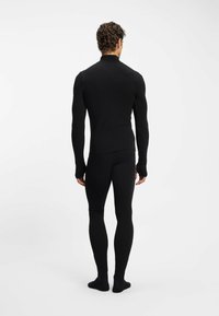 Czarna bluzka z długim rękawem i legginsy wykonane z gładkiej, elastycznej tkaniny; dopasowany fason; bezszwowa konstrukcja; noszone z czarnymi skarpetkami.