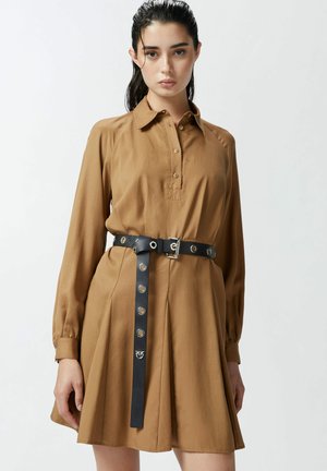 Vestito camicia marrone a maniche lunghe con scollatura a placket e gonna svasata, segnato in vita da una cintura in pelle nera con occhielli metallici e fibbia.
