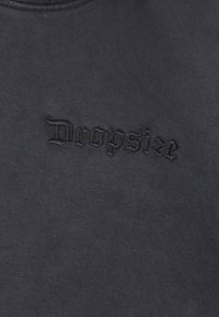 Sort sweatshirts med et præget "Dropsize" logo i mørk tråd. Stoffet har en blød tekstur med en glat overflade.