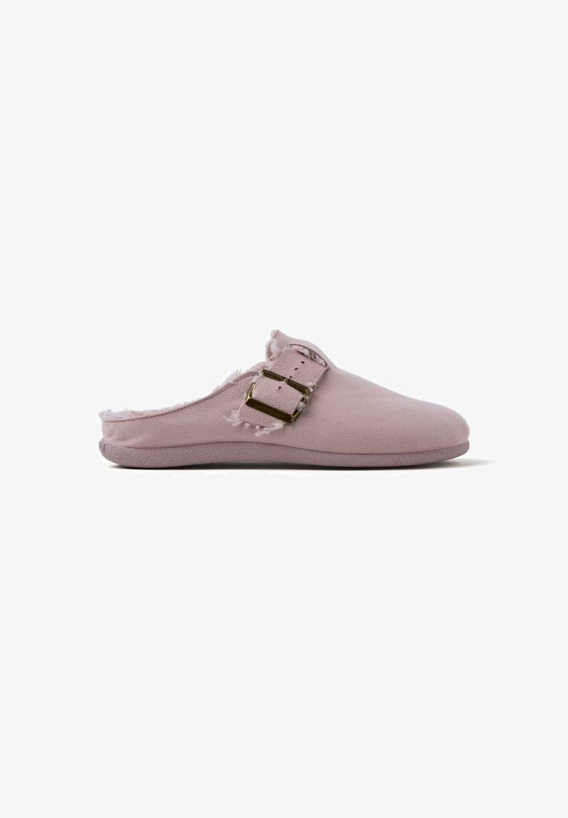 Zapato de ante rosa de tipo slip-on con un interior suave, que presenta un detalle de hebilla dorada y un borde desgastado. Suela plana, punta redondeada.