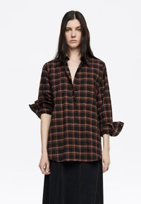 Camisa de cuadros negra y naranja con mangas remangadas y cuello. Fabricada en un tejido ligero y con un corte relajado.