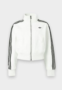 Fehér, derékig érő dzseki magas gallérral, elülső cipzárral és fekete, háromsávos díszítéssel az ujjakon. Kicsi, fekete logó található a mellrészen.