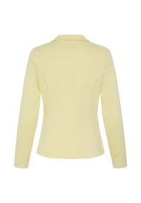 Blazer femme jaune clair taillé sur mesure, manches longues, coutures structurées dans le dos et col à encoche, vu de dos sur fond blanc.