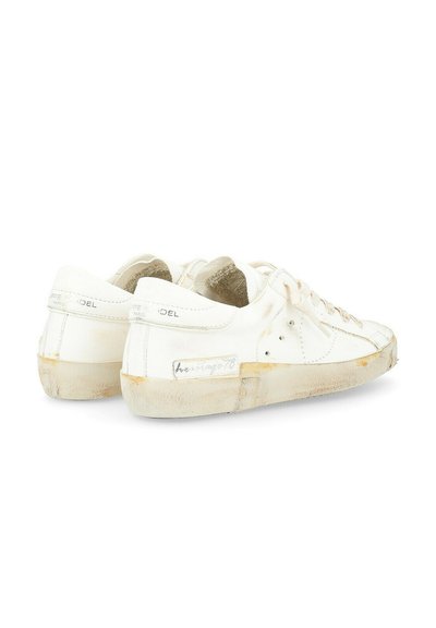 Sneakers bianchi in pelle con un aspetto usurato, caratterizzati da accenti beige, punta rotonda, design alla moda con lacci e suola testurizzata.