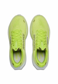 Scarpe da corsa giallo brillante con tomaia in rete traspirante, lacci piatti e suola leggera con il marchio "Brooks" ben visibile.