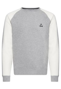 Grå sweatshirt med hvide raglanærmer, rund halsudskæring og et lille sort trekantet logo på brystet. Blødt stof og ribbede manchetter.