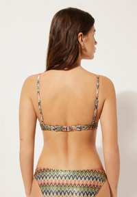 Bunt gemusterter Bikini in Zickzack-Design mit dünnen Trägern und einem Verschluss, der eine Mischung aus grünen, pinken und blauen Farbtönen auf glattem Stoff zeigt.