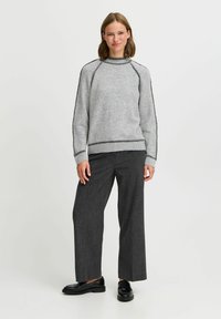 Pulover gri cu guler din tricot, accentuat cu cusături gri închis. Asortat cu pantaloni largi din houndstooth întunecat și mocasini negri.