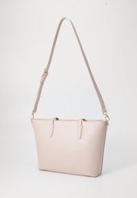 Bēša sintētiska iepirkumu soma ar strukturētu formu, augšējiem rokturiem, regulējamu plecu siksnu un zeltaini metāla akcentiem.