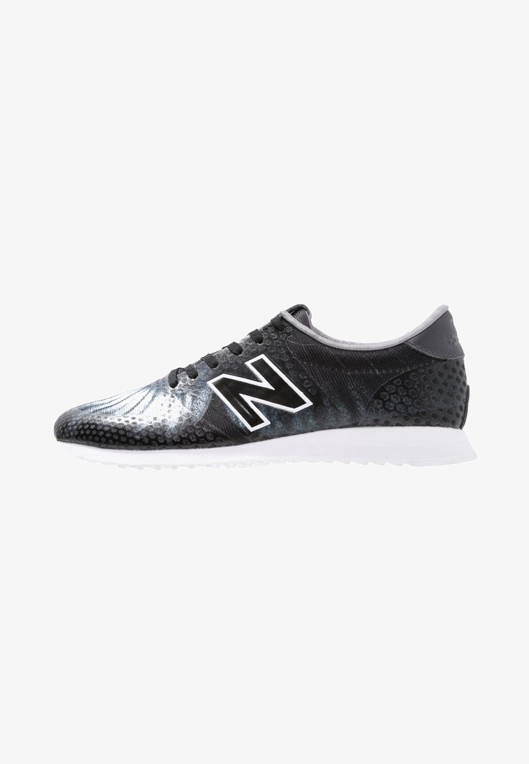 Des chaussures de course noires et grises présentant une tige texturée avec des accents perforés, un logo blanc distinctif et une semelle blanche.