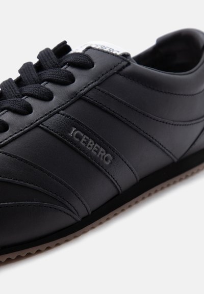 Baskets en cuir noir avec lacets noirs, marque "ICEBERG" embossée sur le côté, et semelle en caoutchouc beige texturée visible sur fond blanc.