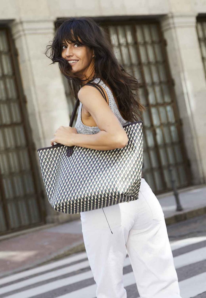 Vävd tygväska i svart, vitt och beige diamantmönster, med två stadiga axelremmar och en strukturerad design.