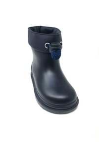 Bota de goma impermeable de color azul marino con superficie texturizada, puntera redonda y suave puño que presenta un acento de cuerda azul y ojales de metal.