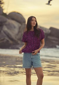 T-shirt à manches courtes de couleur rose vif avec un imprimé léopard noir, associé à un short en denim bleu clair, présentant une coupe décontractée et un ourlet retroussé.