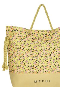 Borsa a spalla floreale gialla con accenti neri, caratterizzata da un corpo testurizzato e un fondo liscio. Ha una maniglia in corda e occhielli metallici.