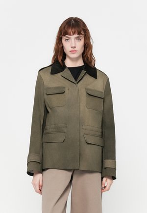 Olivgrüne Jacke mit schwarzem Cordkragen, Fronttaschen und langen Ärmeln. Glatte Textur mit strukturiertem Design.