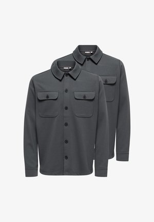 Zwei dunkelgraue Langarmhemden mit Kragen, Knopfverschlüssen und zwei vorderen Brusttaschen mit Knöpfen, auf weißem Hintergrund überlappend dargestellt.