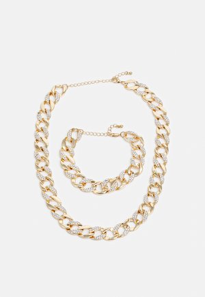 Ensemble de bijoux en chaîne dorée avec de grands maillons et des accents en strass. Comprend un collier et un bracelet, tous deux avec des fermoirs ajustables.
