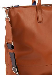 Bruine leren tas met een gladde textuur, voorzien van zilverkleurige hardware en een afneembare schouderband. Een ritssluiting is zichtbaar aan de bovenkant.