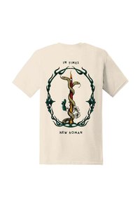 Beige t-skjorte med design av to slanger viklet rundt et tent stearinlys, omkranset av blå, tornete grener, med teksten "IN TIMES" og "NEW ROMAN."