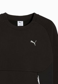 Felpa nera con colletto a girocollo, maniche raglan, tasca con zip e logo Puma bianco sul petto. Tessuto morbido.