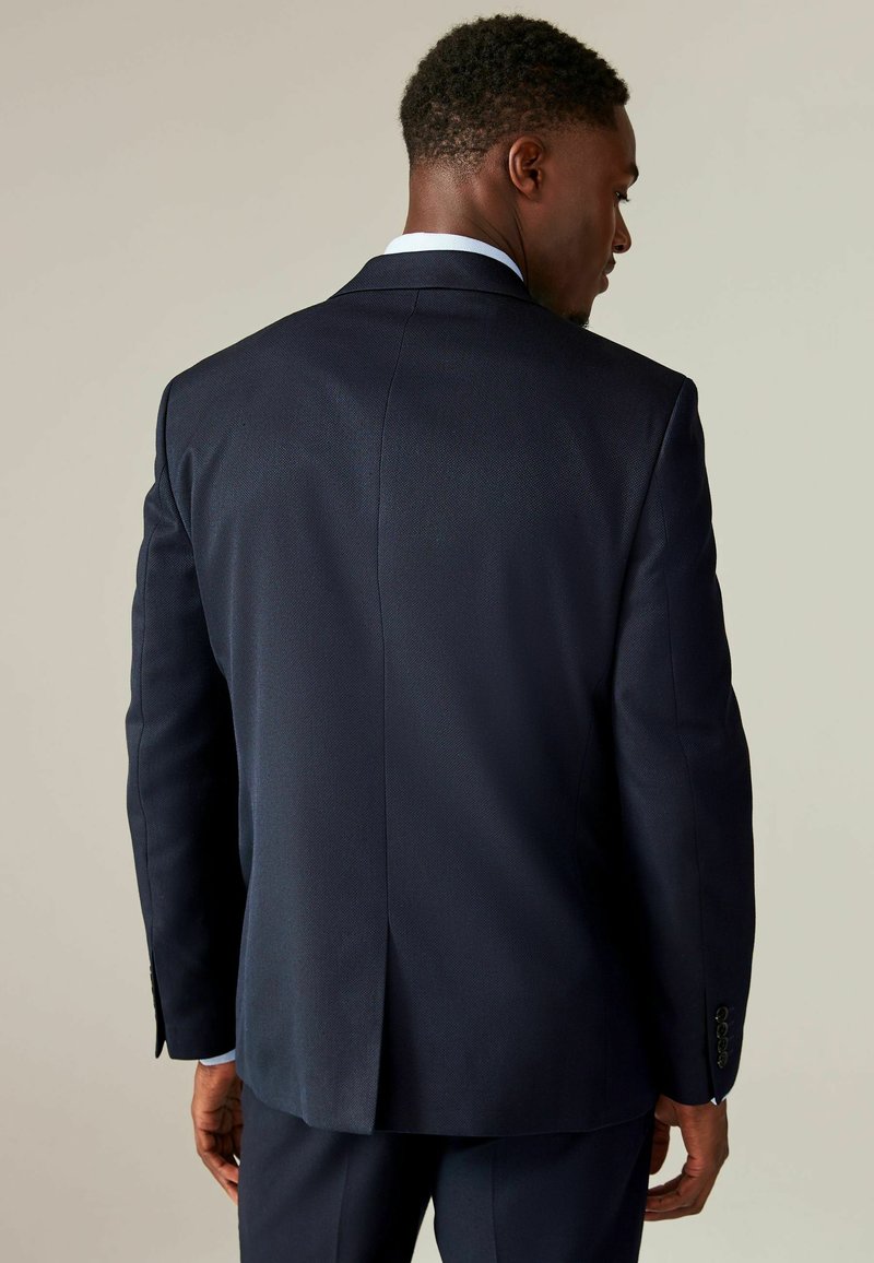 Marineblaues Sakkot, strukturierter Stoff, schmale Rückenbelüftung, geknöpfte Manschetten mit vier Knöpfen, taillierte Passform, minimalistisches Design.
