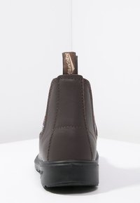 Hnědé kožené kotníkové boty s texturovaným povrchem, barevné pruhované akcenty po stranách a hnědý textilní poutko vzadu.