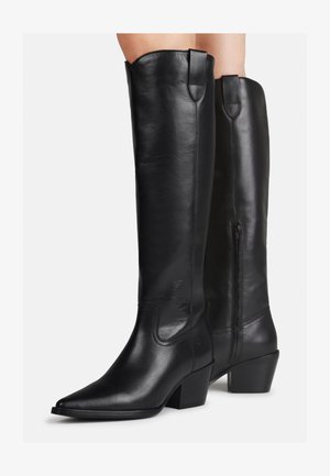 Knielange schwarze Lederstiefel mit spitz zulaufender Zehe, Blockabsatz und dekorativer Naht. Seitlicher Reißverschluss und Zuglasche an der Oberseite für ein einfaches Anziehen.