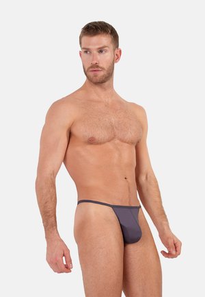 String gris en tissu doux, avec un design minimaliste, une coupe taille basse et des bretelles fines. Texture lisse avec une légère brillance.