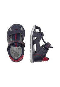 Sandales bleu marine avec accents rouges, sangles ajustables et semelles en caoutchouc. Présente un design ouvert pour la respirabilité et des matériaux texturés.