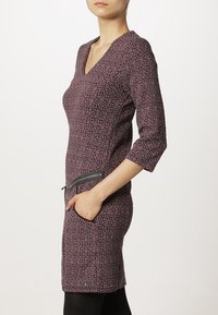 Abito lavorato a maglia di un viola scuro con un motivo testurizzato, caratterizzato da scollatura a V, maniche a tre quarti e una tasca con zip sul lato.