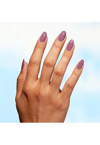 Hand mit länglichen, mandelförmigen Nägeln, die in einer gedämpften Lavendelfarbe lackiert sind. Hautfarbe ist warm, mit sichtbarer Textur und feinen Details.
