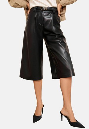Black faux leather culottes with a wide leg cut, featuring front pleats and a belted high waist. Smooth texture with a glossy finish.