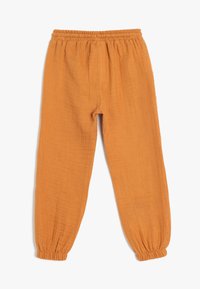 Orange, lette, teksturerede bukser med elastisk talje og draperede manchetter, som har en løs og afslappet pasform.