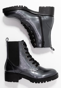 Botines metálicos negros y plateados que cuentan con un cierre de cordones en la parte delantera, cremallera lateral, acabado texturizado y suela gruesa con perfil de tracción.