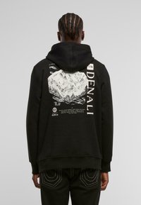 Czarna bluza z kapturem z graficznym nadrukiem góry Denali na plecach, z białymi akcentami i miękką, strukturalną tkaniną.