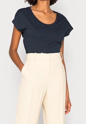 Navy blue short-sleeve top with a scoop neck, made of soft fabric; paired with high-waisted cream trousers featuring a fitted waist and pockets.