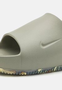 Szürke csúszó szandál textúrázott felülettel, nyitott orral és színes mintázatú talppal. A Nike logó diszkréten kiemelve az oldalán.