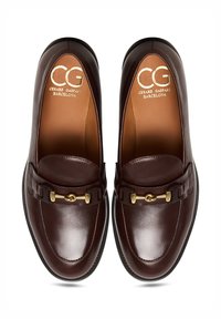 Paar dunkelbrauner Leder-Loafer mit goldener Pferdebit-Detail und braunen Innensohlen, gestempelt mit "CG Cesare Gaspari Barcelona", von oben betrachtet.