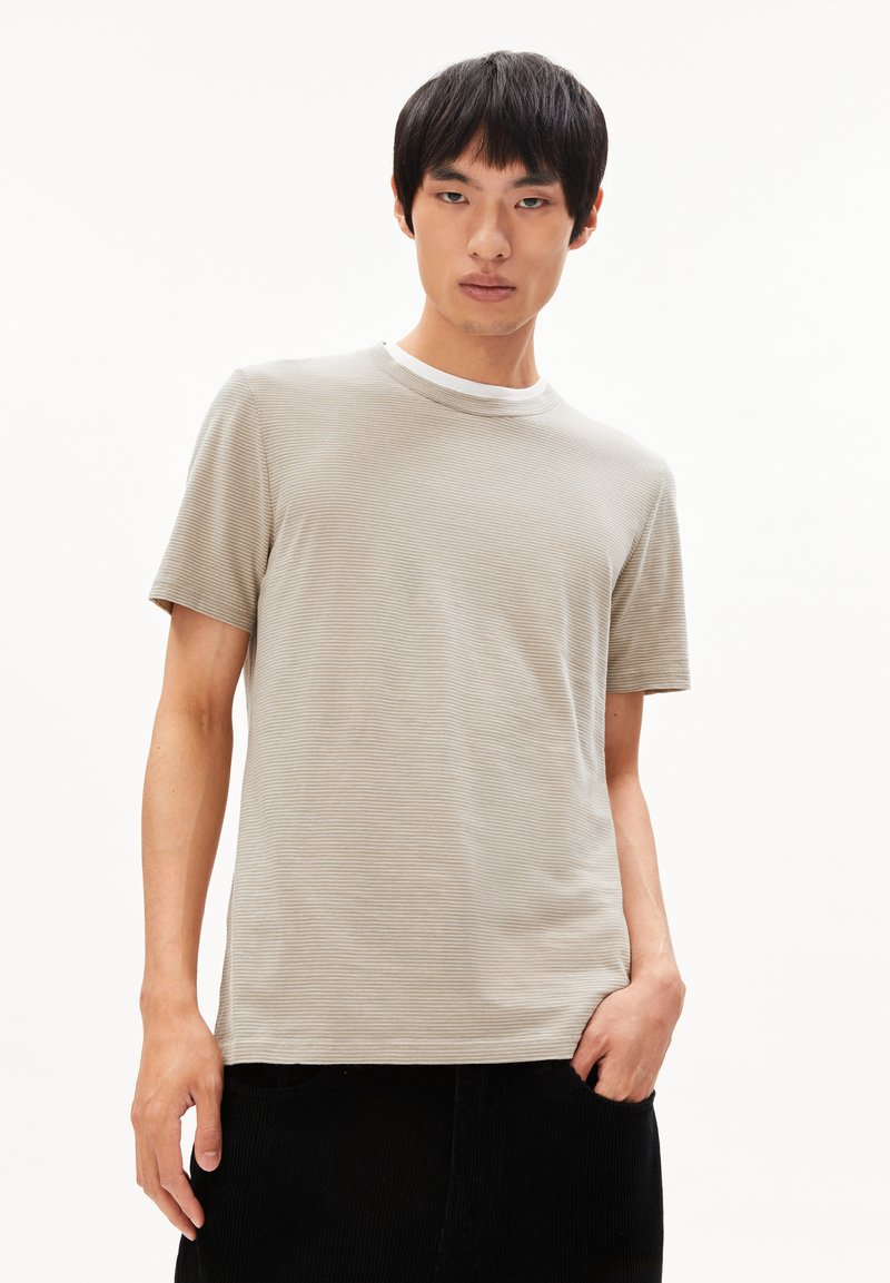 Kurzärmliges, hellgrau gestreiftes T-Shirt mit rundem Ausschnitt, glatter Textur und lockerer Passform. Getragen mit schwarzen Cord-Hosen.