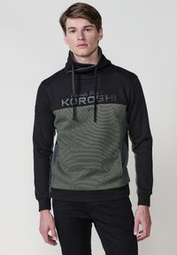 Sudadera con capucha en negro y verde. Presenta un diseño texturizado a rayas y letras en negrita. Incluye cordones y puños de canalé.