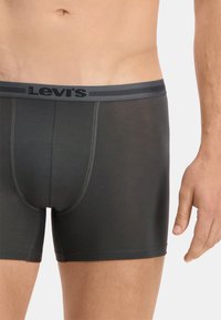 Boxers noirs avec une ceinture élastique grise arborant le logo Levi's. Tissu lisse avec un design ajusté et des coutures plates pour plus de confort.